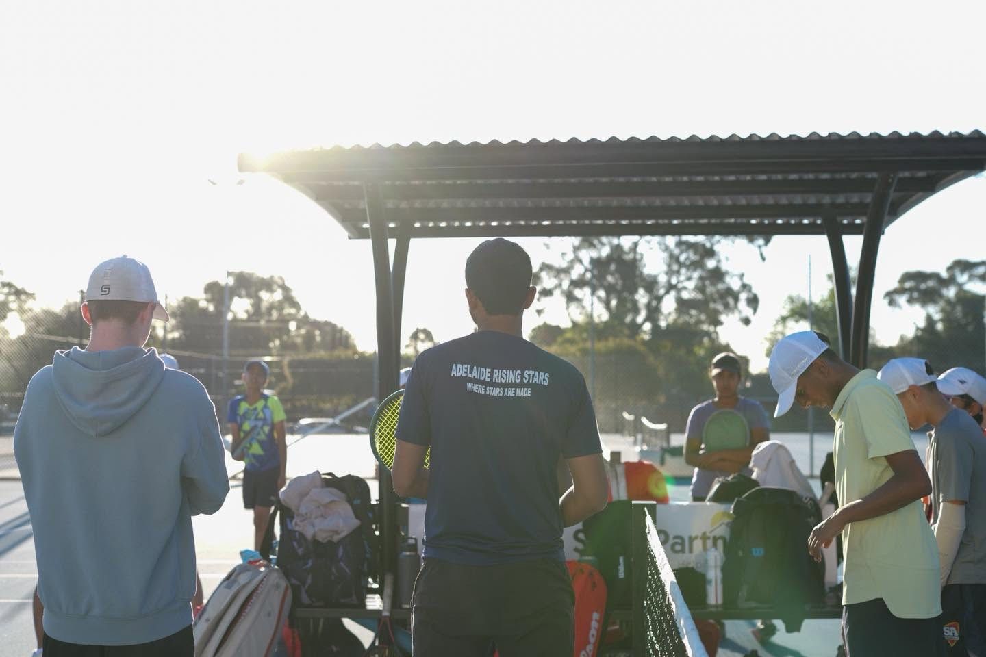Ashwin briefing a group of players courtside at dusk