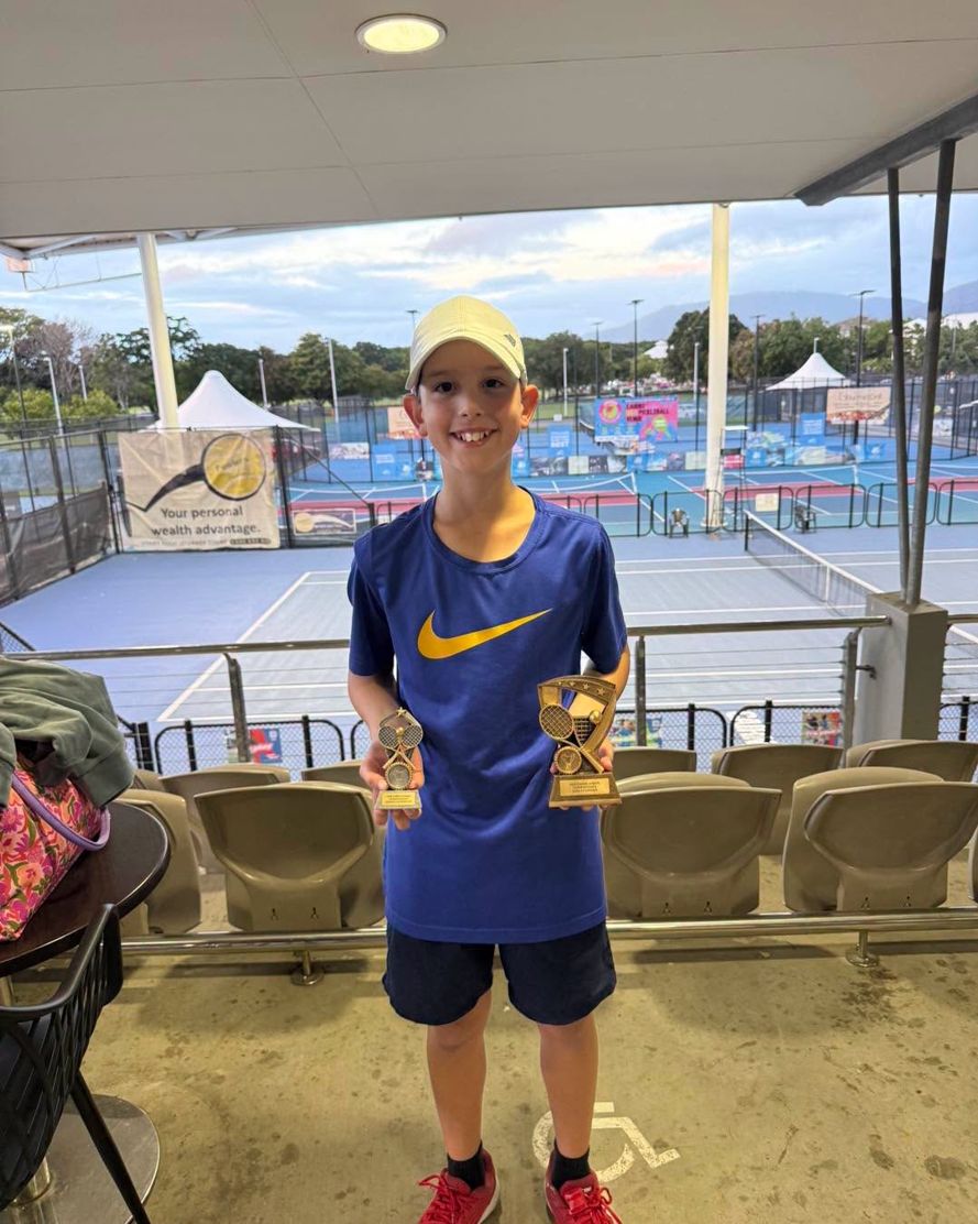 A junior player holding a trophy at a tournament