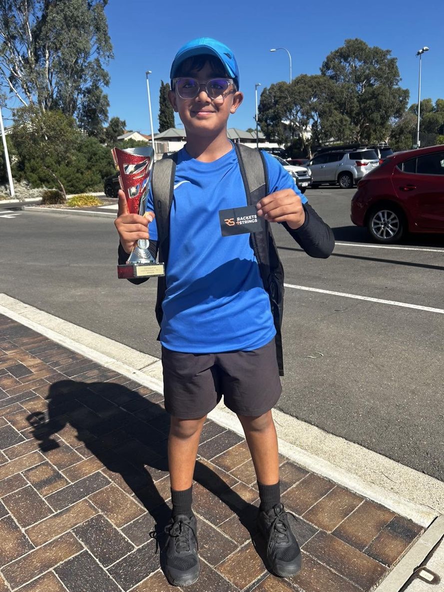 A junior player holding a trophy after a match