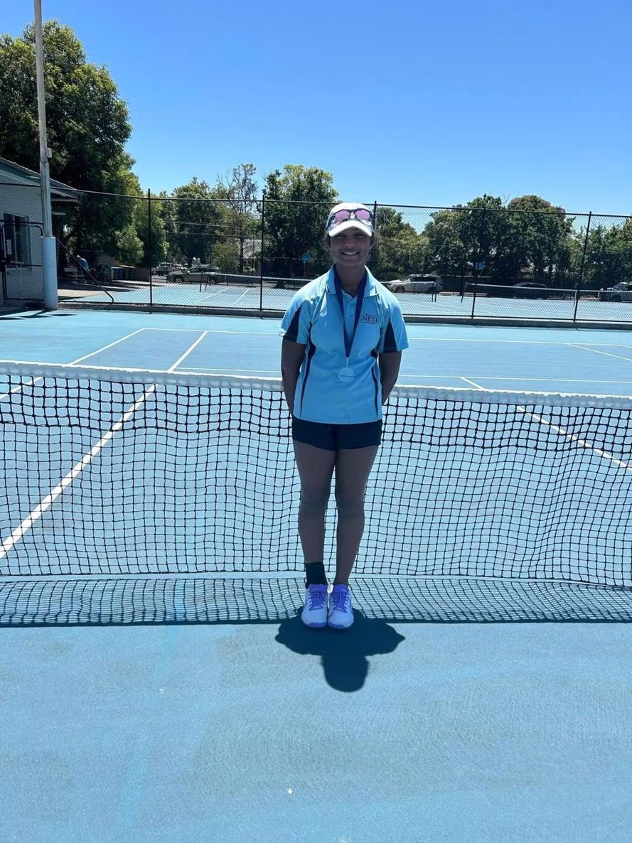 A junior player wearing a medal on court after a tournament