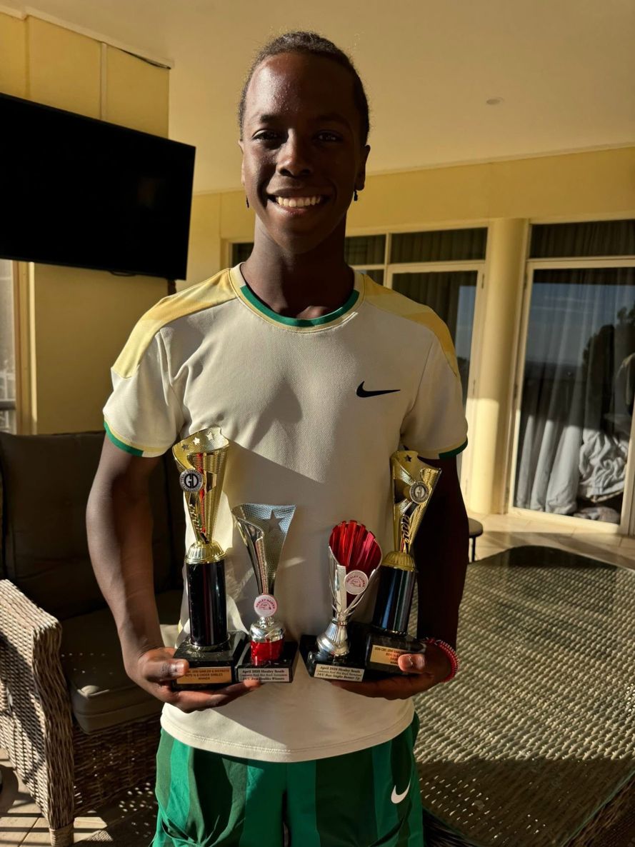 A junior player holding two trophies after a tournament