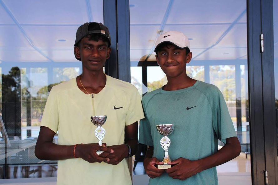 Two junior players holding trophies after a tournament final