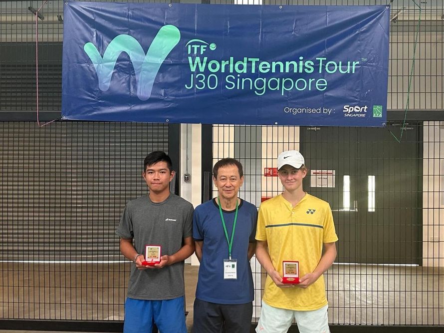 Players with their trophies beneath a tournament banner