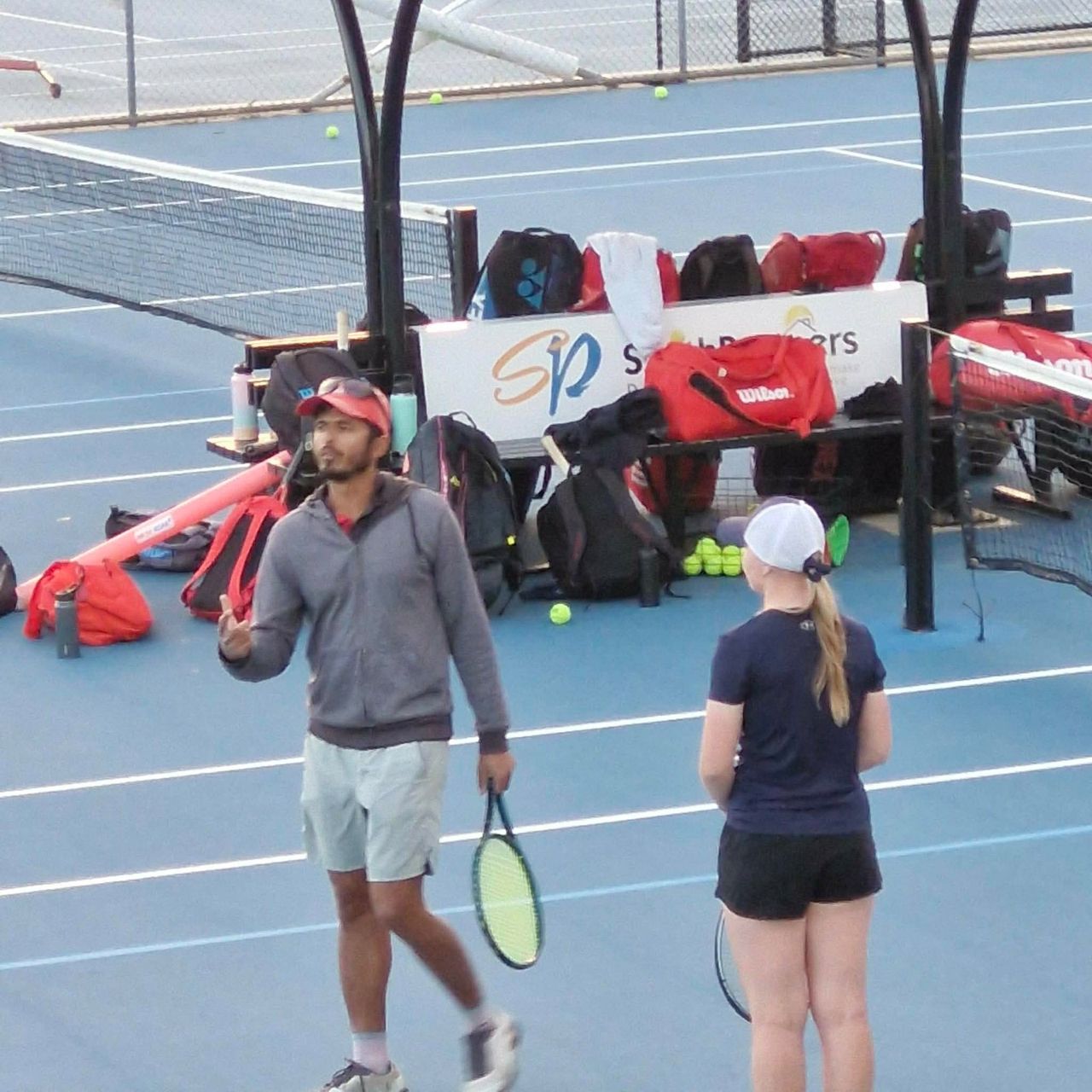 Ashwin talking a junior through a drill on court