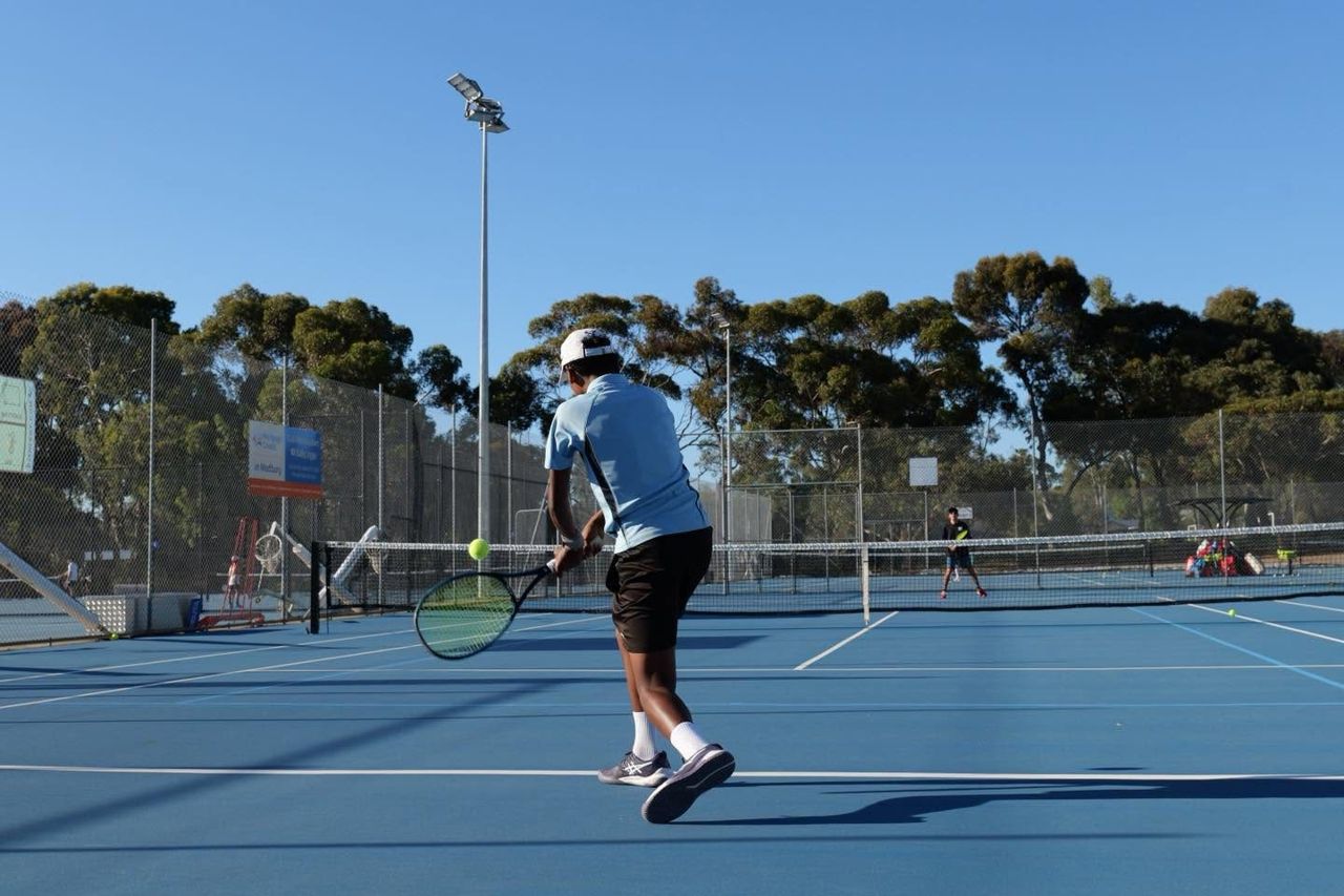 A junior player stepping into a backhand during a match