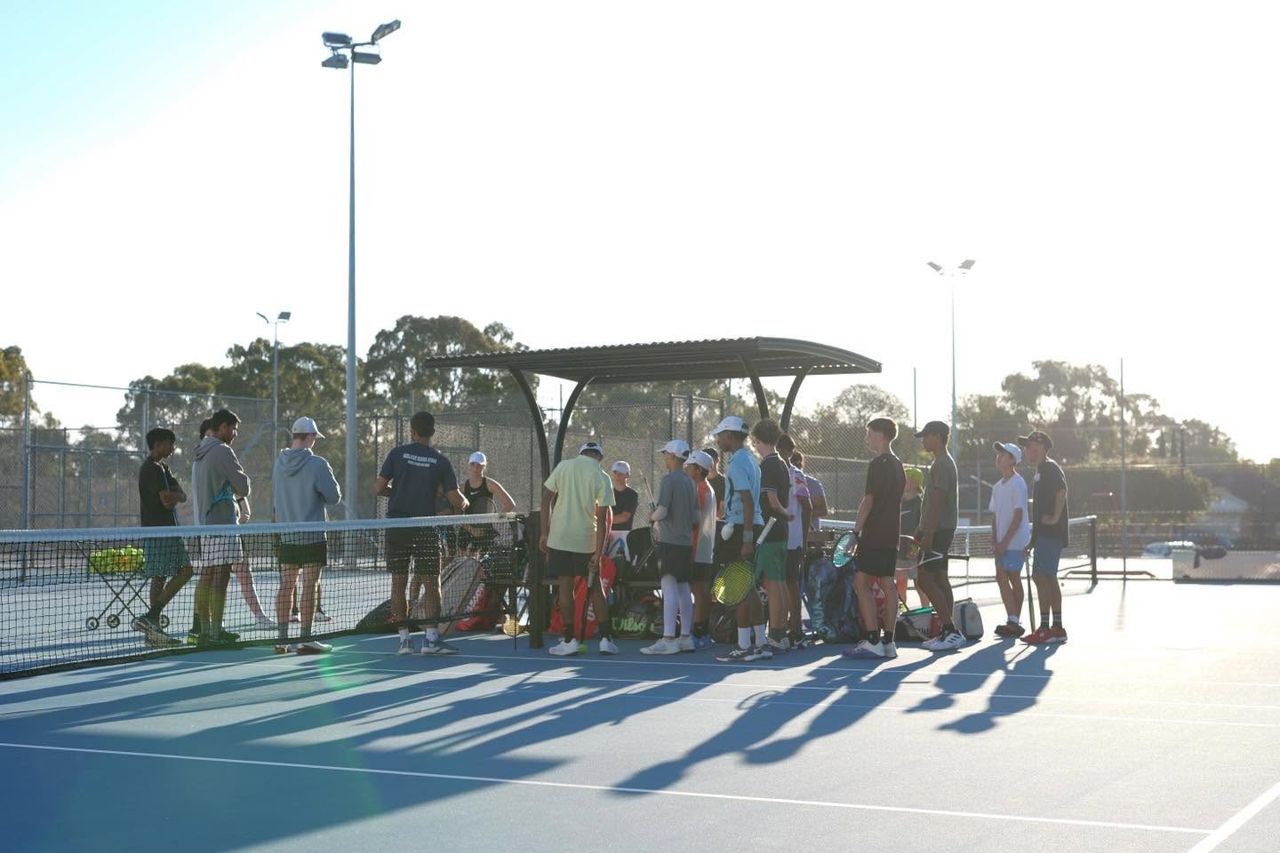 Players gathered courtside with racquets and bags at the start of a weeknight squad