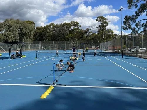 Junior group coaching across several courts, with mini-nets and cones set out
